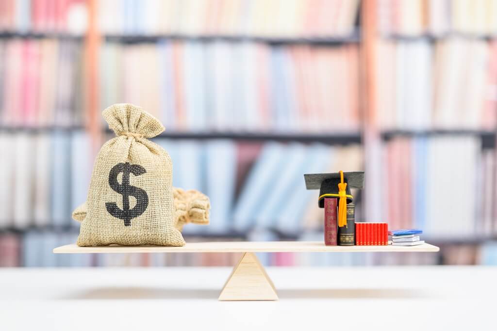 balança com saco de dinheiro, livros e capelo